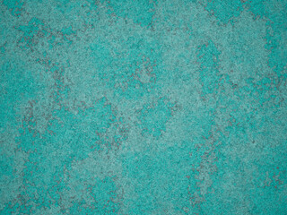A close-up of textured cement surface with hints of turquoise color and grey patterns.