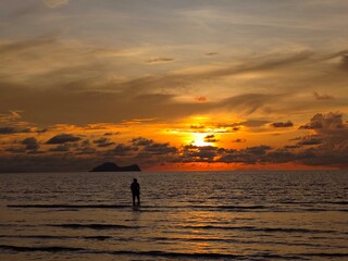 Fototapeta premium silhouette of a man walking on the beach at sunset