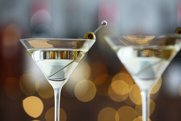 Martini cocktail with olives in glasses on blurred background, closeup. Bokeh effect