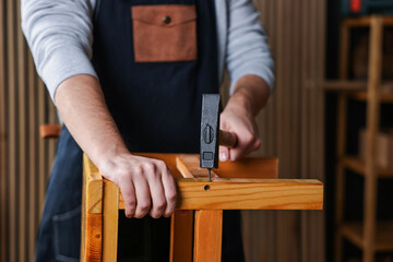 Carpenter repairing wooden stool in workshop, closeup
