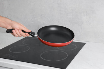 Chef holding frying pan over cooktop in kitchen, closeup