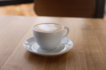 Cup of aromatic coffee on wooden table in cafe