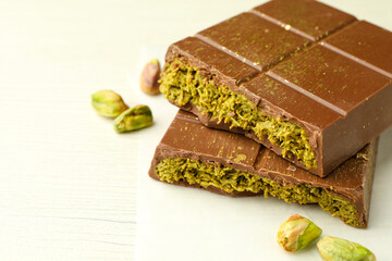 Pieces of tasty Dubai chocolate with pistachios and knafeh on white wooden table, closeup. Space for text