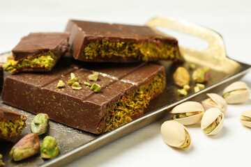 Pieces of Dubai chocolate bars with pistachios and knafeh on white table, closeup