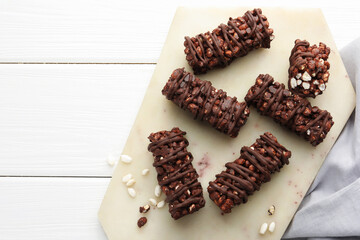 Delicious chocolate puffed rice bars on white wooden table, top view. Space for text