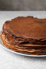 Delicious chocolate crepes on light grey table, closeup