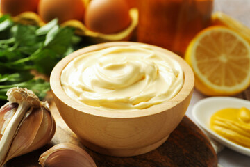 Delicious mayonnaise sauce in bowl and garlic on table, closeup
