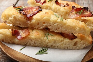 Slices of delicious focaccia bread with bacon and rosemary on table, closeup