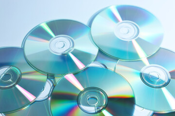 Many shiny compact discs on dusty blue background, closeup