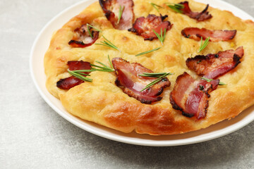 Delicious focaccia bread with bacon and parsley on light grey table, closeup