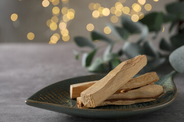 Palo santo sticks and eucalyptus leaves on grey table, closeup