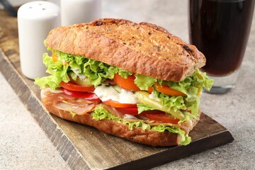 Delicious baguette sandwich with tomatoes and yellow beans on grey textured table, closeup