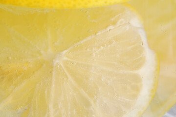 Soda water with lemon slices as background, closeup