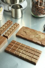 Different tasty Dubai chocolate bars with pistachios and knafeh on grey table
