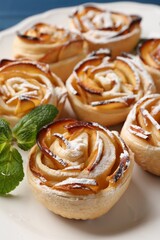 Tasty apple roses with powdered sugar served on table, closeup