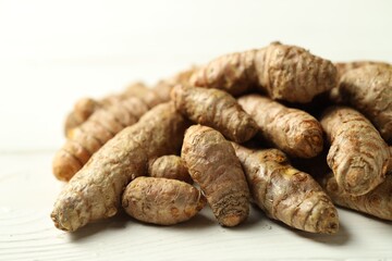 Pile of tumeric rhizomes on white wooden table, closeup