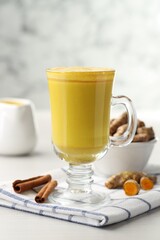 Delicious turmeric latte and rhizomes on white wooden table