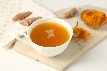 Aromatic turmeric tea, powder and rhizomes on white table, closeup