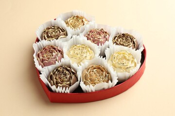 Flower shaped chocolate bonbons in box on beige background, closeup