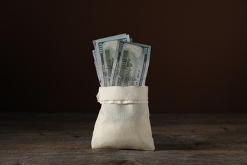 Dollar banknotes in burlap sack on wooden table