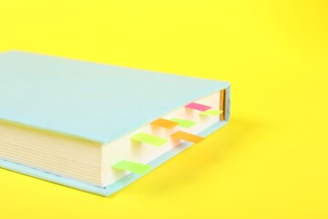 Book with colorful tabs on yellow background, closeup