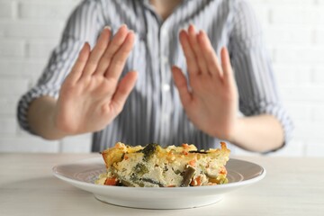Woman refusing to eat piece of casserole at table, closeup