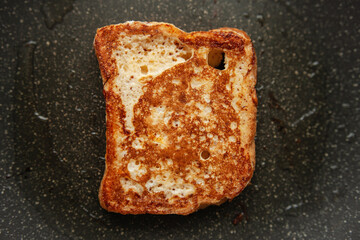 Making French toast, close-up of a nicely golden piece of French toast cooking in a skillet,...