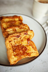 French toast with honey, traditional sweet homemade breakfast of bread soaked in eggs and milk, served on a white plate and shot in bright morning light 