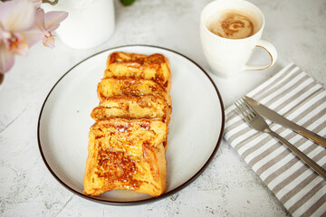 French toast with honey, traditional sweet homemade breakfast of bread soaked in eggs and milk, served on a white plate and shot in bright morning light with copy space 