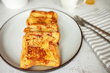 French toast with honey, traditional sweet homemade breakfast of bread soaked in eggs and milk, served on a white plate and shot in bright morning light with copy space on right side