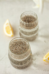 Two glasses of healthy drink to start the day - chia water with lemon on white background, great for hydration, digestion and detox, shot in bright morning light