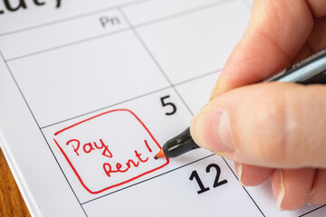 Rent Pay Due Date In Calendar. Close up of pay rent written on date with red marker.