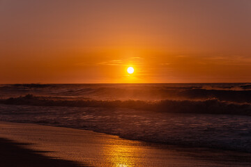 The most beautiful sunset on the ocean coast. Golden hour on the beach. The sky in bright colours of the sunset and the calm ocean