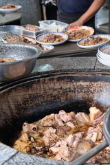 meat fried in a large cauldron in the kitchen of an Uzbek cafe