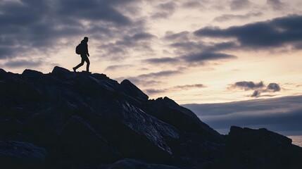 Silhouette of a lone hiker standing atop a rocky mountain ridge overlooking a breathtaking sunset landscape with dramatic clouds and majestic peaks in the distance