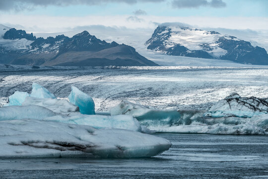 A spectacular Arctic landscape in Iceland’s Jökulsárlón Lagoon, where large blue icebergs float on the water, creating a mesmerizing natural sight