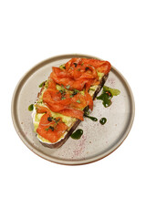 Delicious bruschetta topped with smoked salmon and herbs on a rustic plate. Isolated on white background.