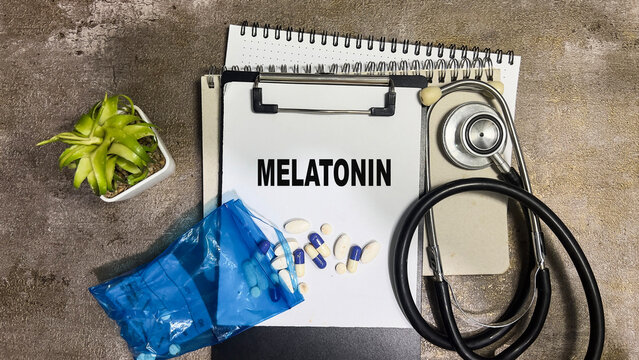 Concept of Melatonin write on paperwork isolated on Wooden Table.