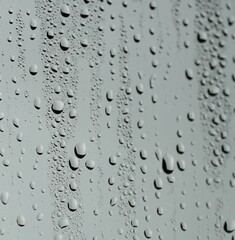 Water drops on grey glass surface, closeup