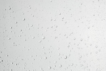 Water drops on light grey glass surface, top view