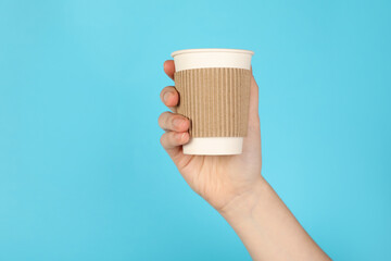 Woman holding paper cup on light blue background, closeup. Mockup for design