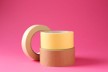 Rolls of different masking tapes on pink background