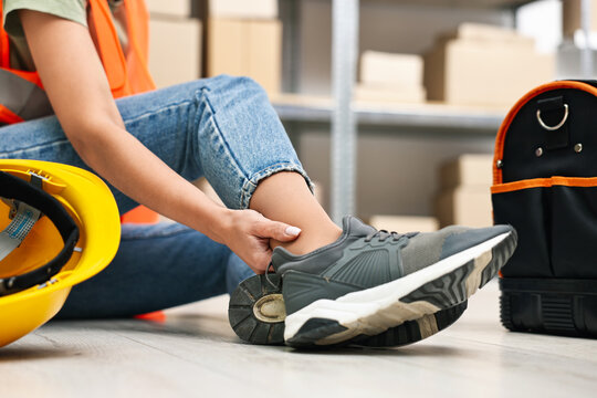 Accident at work. Woman with injured leg on floor indoors, closeup