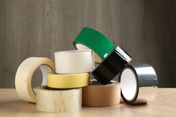 Rolls of different adhesive tapes on wooden table