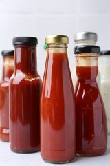 Tasty sauces in glass bottles on white table, closeup