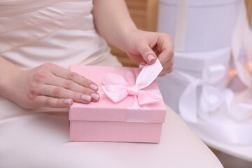 Bride opening beautiful wedding gift indoors, closeup. Space for text