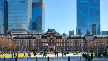 A historic train station with Neo-Baroque architecture and a red-brick facade faces a spacious plaza filled with commuters and tourists. The scene is set under a bright winter sky, with towering steel © Pix4Japan