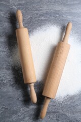 Rolling pins and flour on grey textured table, flat lay