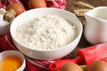 Rolling pin and ingredients for dough on table, closeup
