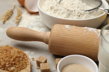 Rolling pin and different ingredients on light table, closeup